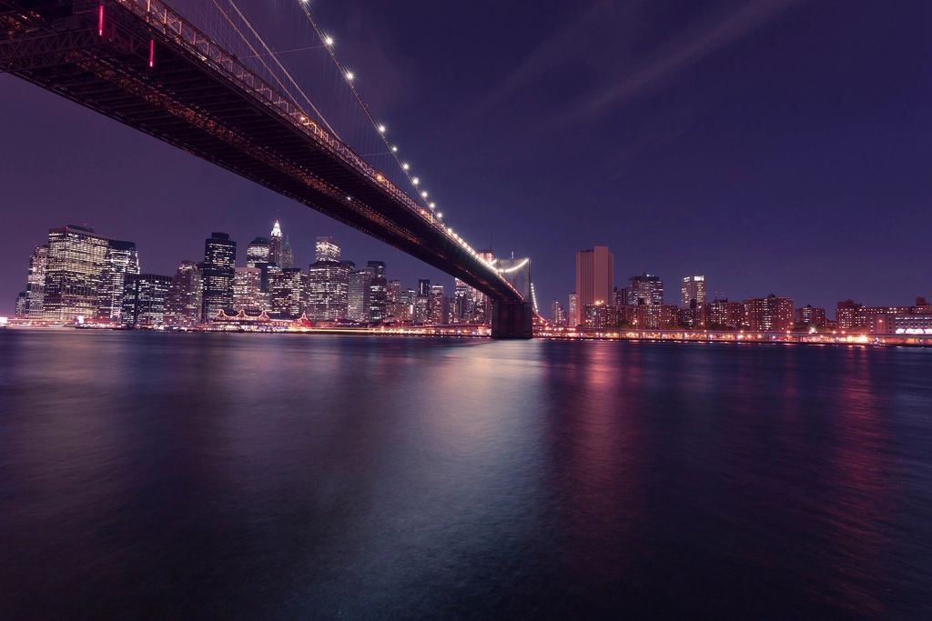 The Manhattan skyline at night, seen from beneath the Brooklyn Bridge